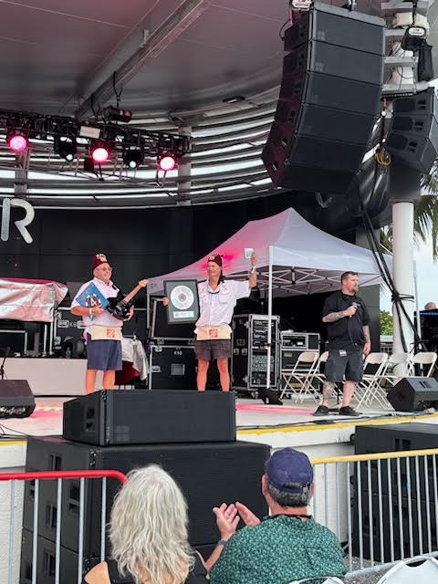 Two Shriners on stage at a Foreigner concert holding the signed guitar raffled to raise money for the club.