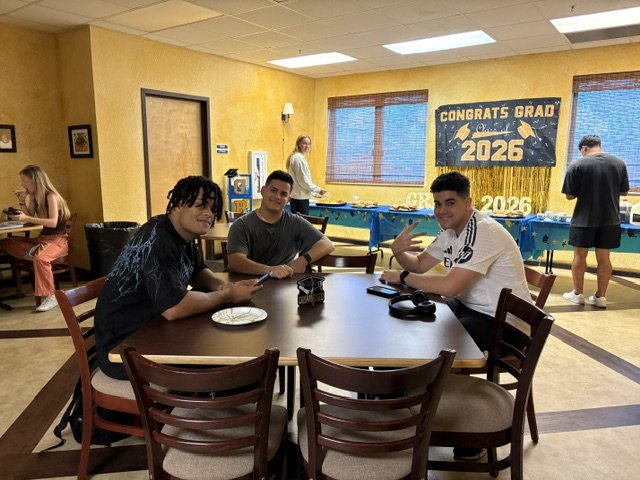 Three Class of 2026 students at the Shrine Club's scholarship reception, gathered around a table in the clubhouse.