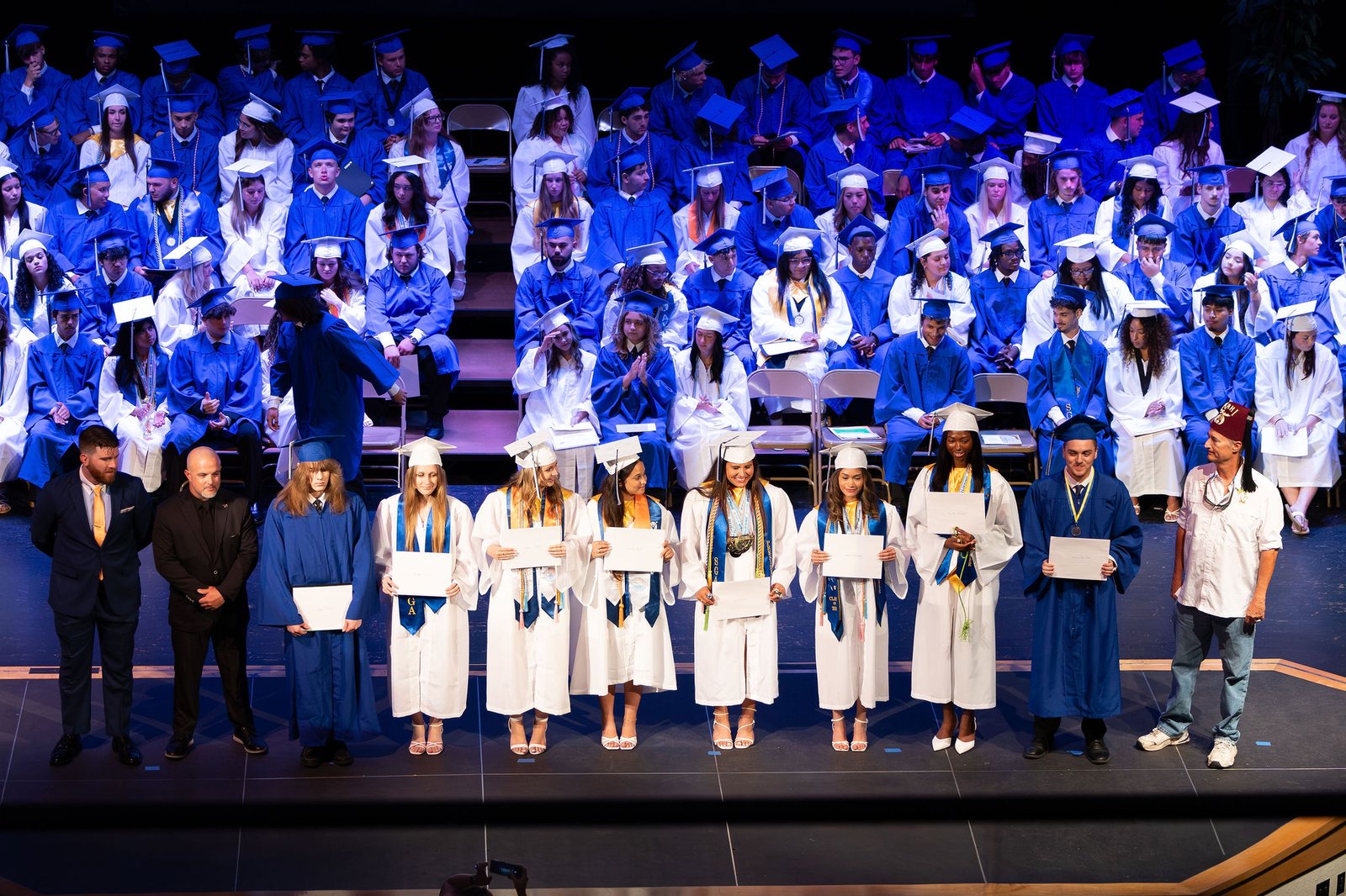 Class of 2026 graduates on stage with Marathon Shrine Club members presenting scholarship awards.