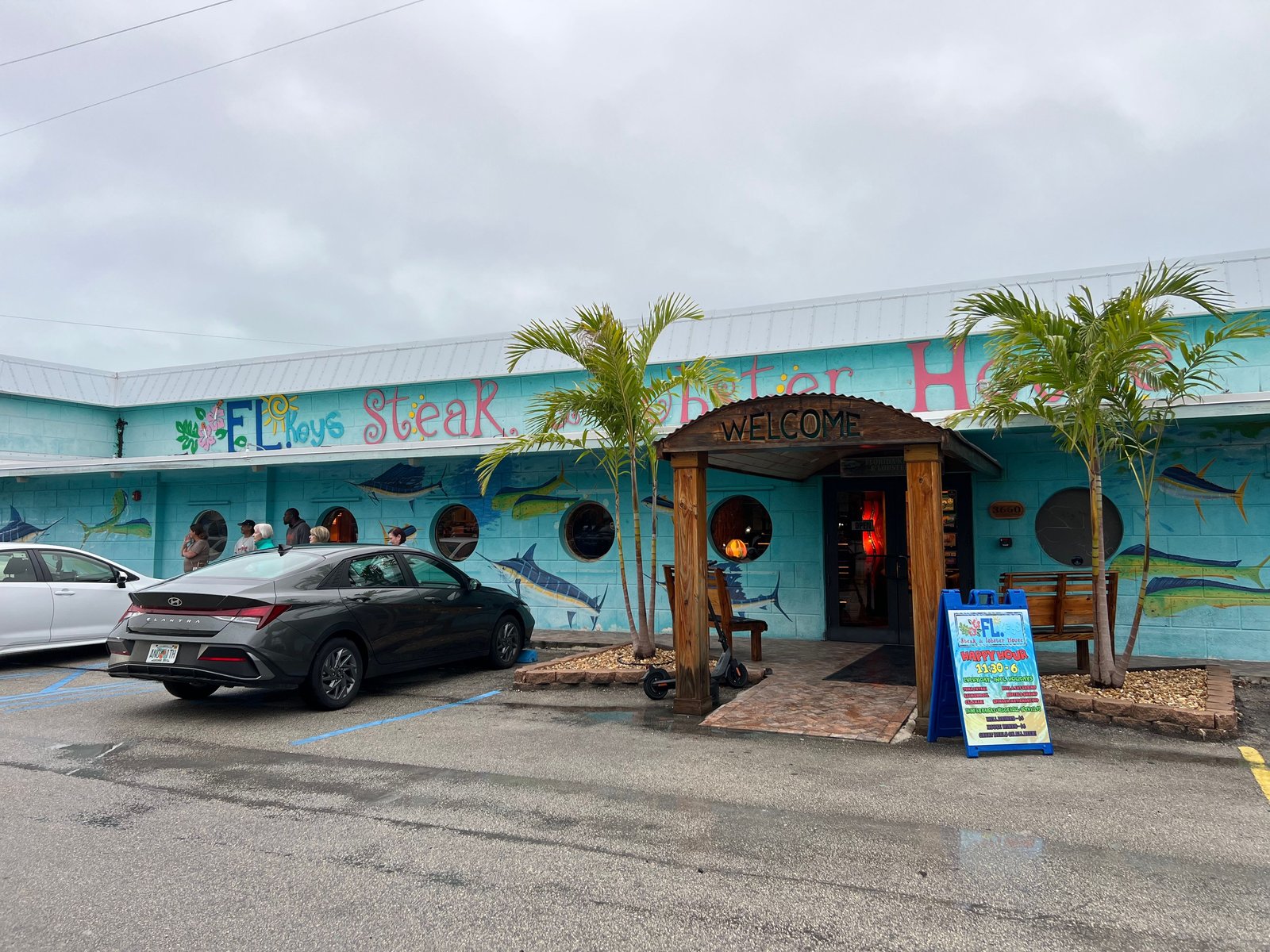 The Florida Steak and Lobster House exterior in Marathon, FL, with marlin murals on the turquoise walls and a covered welcome entryway.